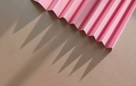 Minimalist template with copy space by top view close up macro photo   with  corrugated pink paper and hard stretched sharp shadows natural sunlightの写真素材