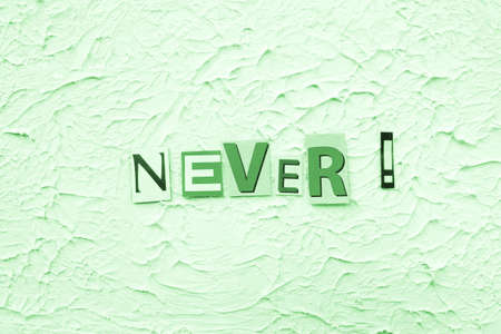 carved paper color letters and the word "Never" composed on green textured embossed backgroundの写真素材