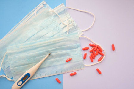 Medical mask, red capsules and electronic thermometer, Concept of medicine and health. Against...