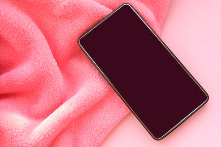 Pink delicate background of nice furry cloth, Soft loose folds on the fabric of faux fur and with Smartphone black screen mockup, romantic backdrop and place for love textの写真素材