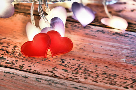 Two red hearts and sparkling festive garland in dark settings. Desktop, copy space. vintage style. Concept of love and romance. Beautiful background for Valentines Day.の写真素材