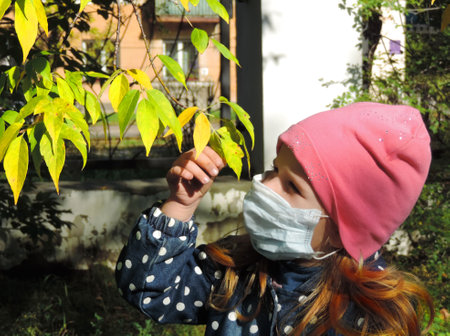 girl child puts on a medical mask and walking in the parkの写真素材