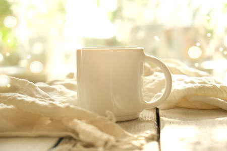 Soft focus, Cup of coffee and folds plaid on wood table with  bokeh background and sunlight. Cozy  interior. Beautiful light.の写真素材
