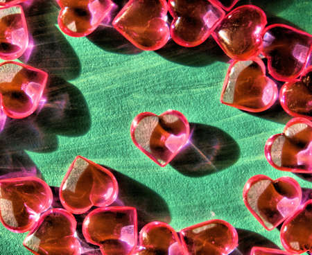 Crystal hearts on green painted surface, brurred, hard shadow, copy space. Holiday banner, web poster, flyer, greeting card, cover. Romantic backgroundの写真素材