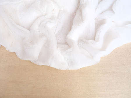 White delicate soft background of plush fabric folds on light golden background with shadow and...