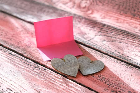 Empty pink blank card and two heart. Sunrise morning light and shadows. At home. love concept.