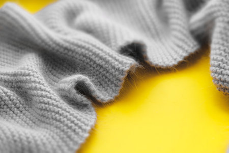 Blurred Gray knitted scarf asymmetrical frame  on yellow .  Symbolize warmth, love and tenderness. ...