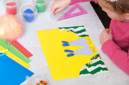 Child making card with Easter bunnies toys from colorful paper and placticine. Handmade. Project of children's creativity, handicrafts, crafts for kids.の写真素材