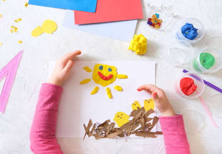 Child making spring card from colorful paper and clay. Handmade. Project of children's creativity, handicrafts, crafts for kids.の写真素材