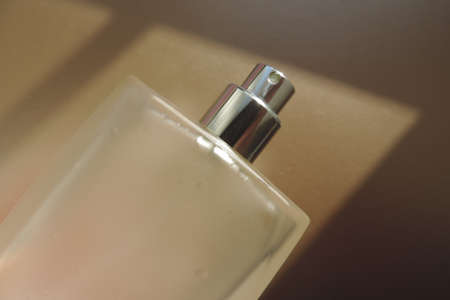 Bottle of essence perfume on pastel beige background with sunlight and shadows. Minimal style perfumery templateの写真素材