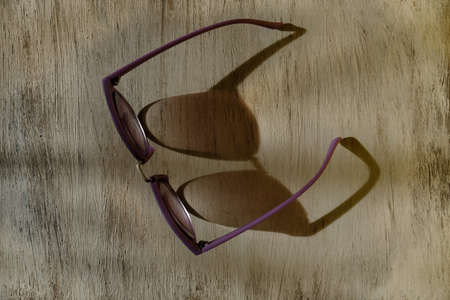 Stylish sunglasses on wooden background, sun light and strong shadows, fashion and summer vacation concept.の写真素材