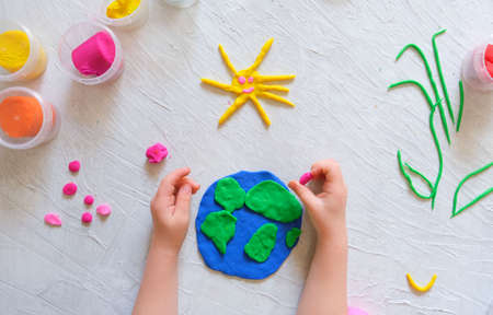 Child sculpturing plasticine planet for earth day. Protection of environment, Save our planet. Ecology concept. Concept of art learning and education, love earth, save world and unity.の写真素材