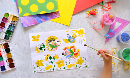 Child making homemade greeting card. little girl making applique with birds and flowers from pieces...