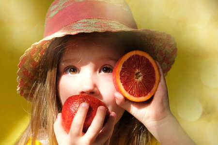 Cute little girl in straw hat licking orange fruit. gift tour for all family. Happy weekend. Health diet.の写真素材