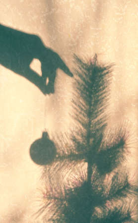 blurred view shadow on beige wall with neutral pattern female hand and christmas toy ball, authentic home conceptの写真素材