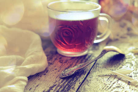 Cup of tea, neutral scarf on wooden table, sun glare and bokeh, the concept of home comfort, retro atmosphere. Romantic morningの写真素材