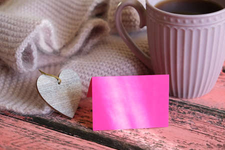 Partial blurred cozy still life with cup of coffee warm scarf and empty card, copy space, Sunrise morning light and shadows. At home. love concept.の写真素材