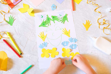 Child making homemade greeting card. little girl making card for mom with flowers from paper as gift for Mothers day, Birthday or Valentines day. Arts crafts concept.の写真素材