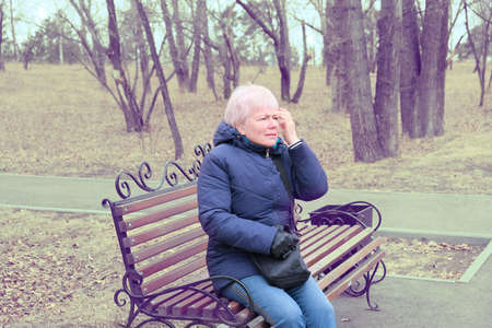 Senior Woman Relaxing On Park Bench. Retro filter.の写真素材