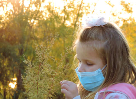 preschool girl in Medical blue disposable protective mask at the evening for a walk at sunset
