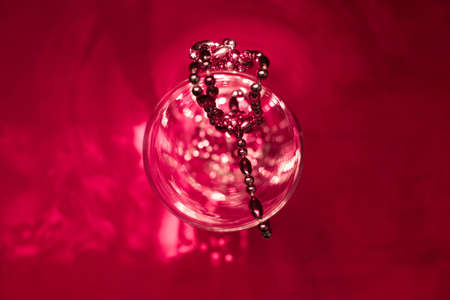 Abstract red background with glass vase and beads, reflection, shadow, sunlight, minimal natural luxury, copy spaceの写真素材