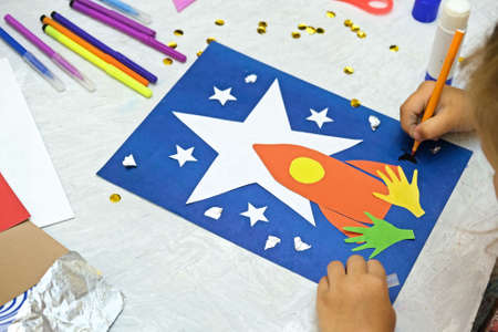 Child making rocket and stars from paper. Creative children play with craft. The space theme development of children.  School education handmade creativity.の写真素材