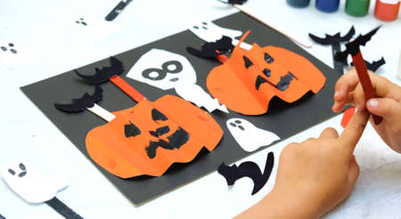 Child making pumpkins for the holiday of halloween. Funny crafts from paper. Halloween decor. Handicraft. The concept for Halloween. DIY. Children's art project, a craft for children.の写真素材