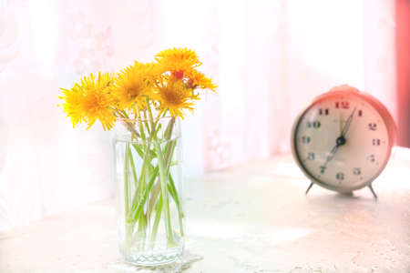 Cozy summer still life with flowers of and alarm clock on the table. At home. Rustic style, Lazy...