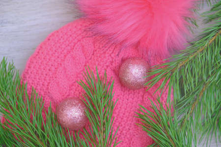 Pink knitted woolen cap. Christmas background with winter style hat near pine branches on rustic...