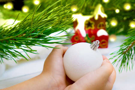 Hands of little girl holds decorative Christmas ball toy for decorate Christmas tree branches. Christmas and new year family celebration conceptの写真素材