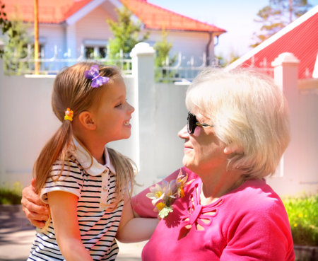 Loving cute granddaughter hugging her grandmother. Happy family.  Having good times with grandparent outdoors.の写真素材
