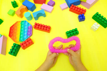 Child playing with antistress sensory toy fidget push pop tube and other toys. Silicone toy...