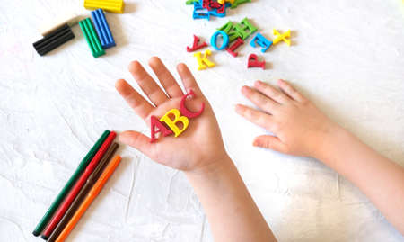 child holding ABC letters in hands over desk table background Education and development concept.の写真素材
