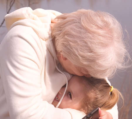 Loving grandmother hugging her granddaughter. Having good times with grandparent outdoorsの写真素材