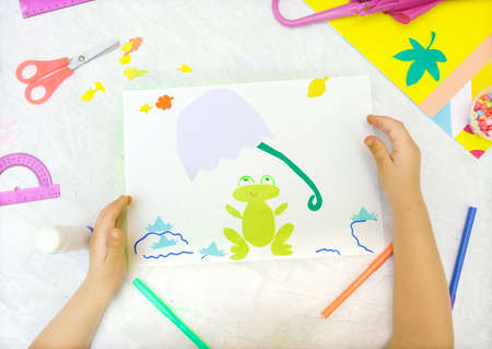 Autumnal craft application. Child cutting from paper frog and autumn leaves, making sun from...