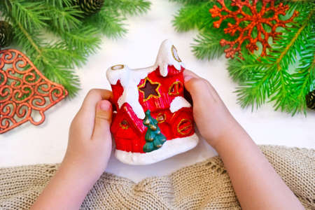 Hands of little girl holds decorative Christmas house toy for decorate home. Christmas and new year family celebration conceptの写真素材