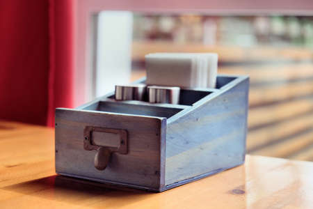 Cutlery is on the table in the restaurant. Napkin holder, pepper pot, salt shaker. Handmade vintage wooden holder for cutleryの写真素材