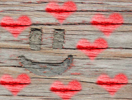 a smiling face is carved on an old wooden surface, and toning red heartsの写真素材