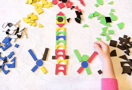 Childrens mosaic, a game for creativity, little girl playing with colorful details of mosaic,...
