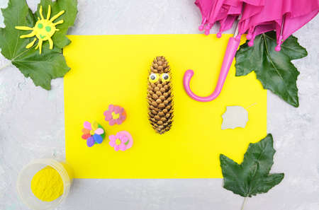 Autumn crafts. Child making fun butterfly from natural cone and leaves use paper and plasticine....