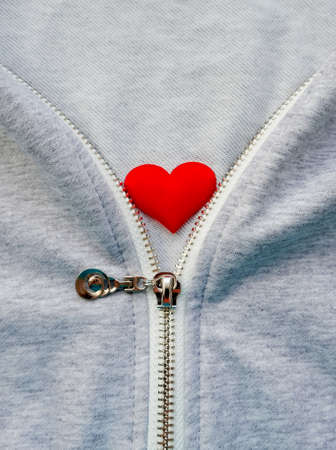 Slider in zipper on textile gray melange woolen clothes and red heart inside. Concept of love, kindness, loyalty and generosityの写真素材