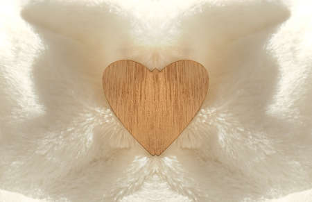 Wooden heart on white fluffy plaid folds. concept of love and romance. Beautiful background for Valentine's Day.の写真素材