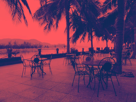 Blurred view street cafe  with tables outside  at dusk late evening , no people empty tables, red vintage tonedの写真素材