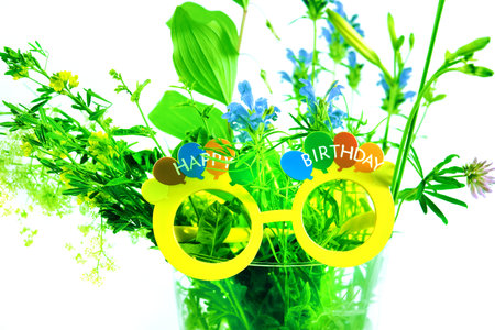 Colorful fresh summer bouquet flowers in glass vase and decorated eyeglasses with Happy Birthday textの写真素材