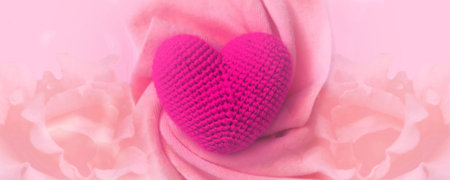 Wide banner with  crochet heart and soft warm  scarf,  pastel floral background with copy space. Love , romance, wedding, boho styleの写真素材