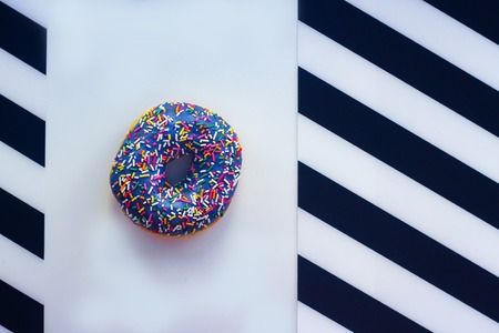 sweet Donut with icing and color dusting, on a white background with black and white stripes on the sides, top viewの写真素材