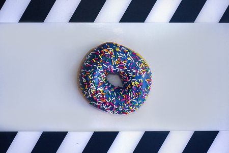 sweet Donut with icing and color dusting, on a white background with black and white stripes on the...