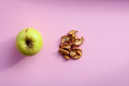 Healthy snack. Homemade sun-dried organic Apple slices, crispy Apple chips, on pink background. top viewの写真素材