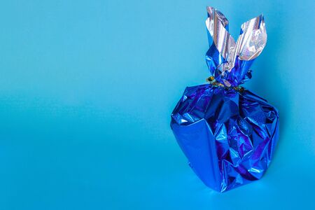Silhouettes a rabbit in a packing festive blue paper behind a blue backgroundの写真素材