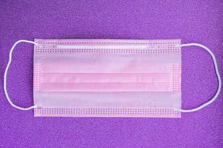 Pink medical mask, Medical protective mask on violet background. Coronavirus hygiene conceptの写真素材